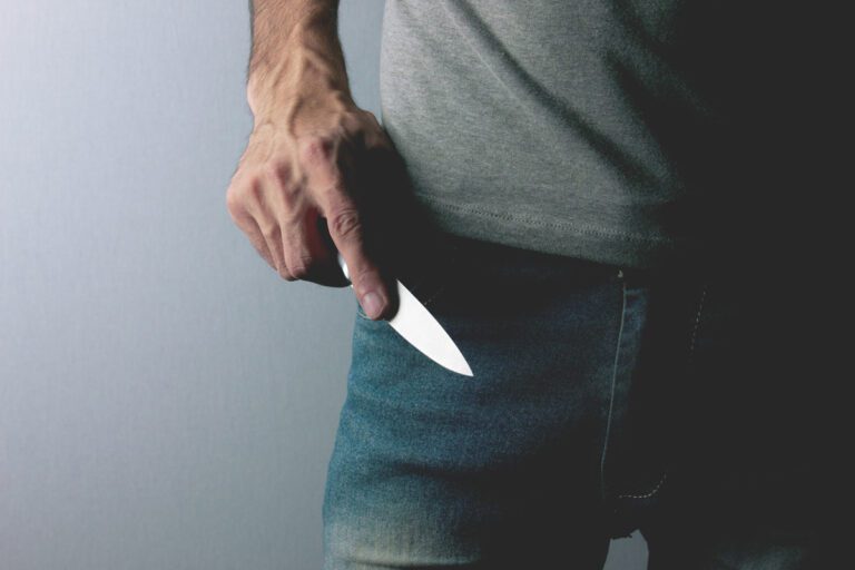 Ein Mann hält ein Messer in der rechten Hand und ist bereit dieses als Waffe zu benutzen
