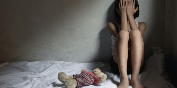 hilfloses Kind nach Missbrauch und Vernachlässigung sitzt auf einem ungemachten Bett