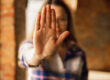 Nahaufnahme einer jungen Frau die eine STOP-Geste mit ihrer Hand macht und damit klare Grenzen aufzeigt