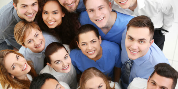 Mitarbeiter aus der Pflege und Verwaltung stehen als Team gemeinsam. Alle lächeln zufrieden und entspannt.