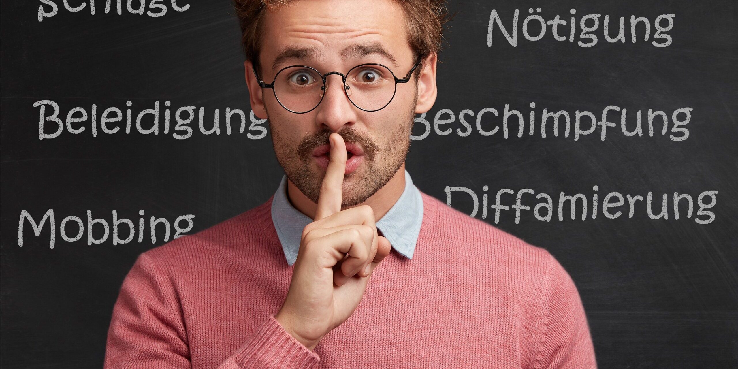 Lehrer vor einer Schultafel mit Begriffen zu verbaler und körperlicher Gewalt hält den Finger vor die Lippen, um zu zeigen, dass das Thema Gewalt gegen Lehrer häufig totgeschwiegen wird